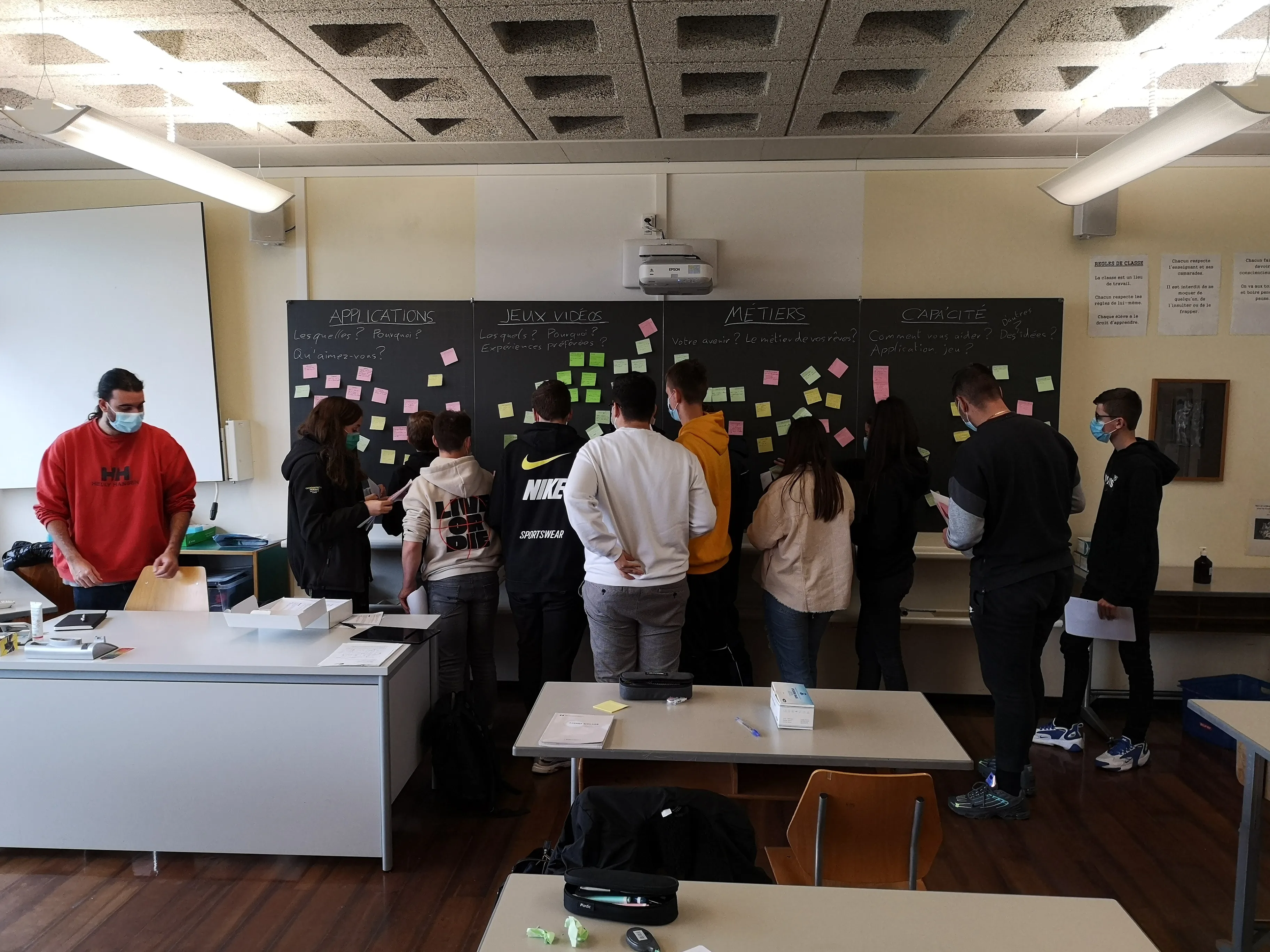 Atelier de design thinking avec des élèves autour d'un tableau couvert de post-its